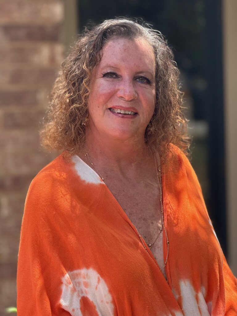 Shelby smiling in an orange dress